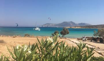 Kiteboarding and sailing in a vibrant turquoise sea with mountains in the background.