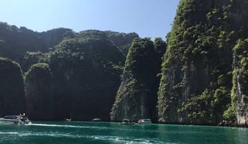 Tall limestone cliffs rising from the sea with boats at the base.