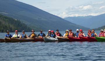 Group of people kayaking on a lake with mountains in the background.