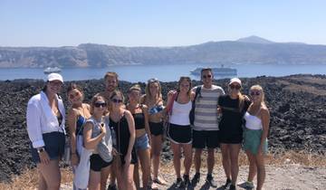 Group of people on a hill with a cruise ship in the background.