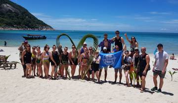 Large group on a beach, holding a blue flag.