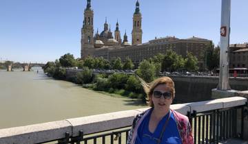 Person standing near a river with cathedral in the background.