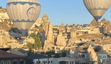 Hot air balloons above a rocky landscape and buildings