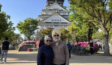 Two people posing in front of a Japanese castle.