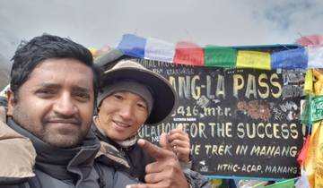 Two people taking a selfie in front of a sign reading 'Thorong-La Pass'.