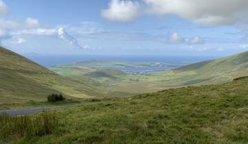 Panoramic view of a green valley with ocean in the background.