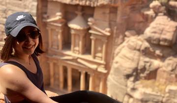 A woman posing on a cliff with the iconic Petra Treasury visible in the background.