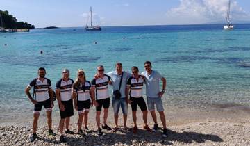 Group of cyclists posing on a pebble beach with calm sea in the background.
