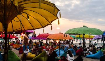 Beach scene with colorful umbrellas and bean bags at sunset.