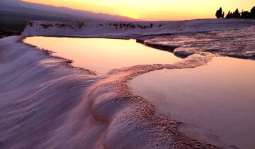 Sunset over Pamukkale terraces reflecting the orange sky.