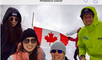 Group of people holding a Canadian flag on a snowy landscape.
