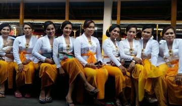Women in traditional dress sitting on benches, smiling.