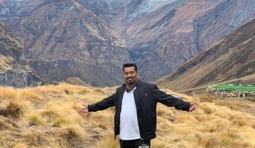 Person posing with arms outstretched in a mountainous landscape.
