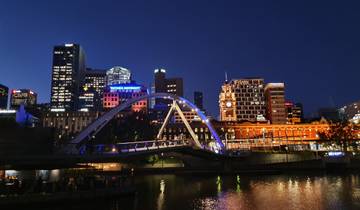Cityscape at night with illuminated buildings and bridge.