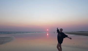 Person posing on a beach during sunset.