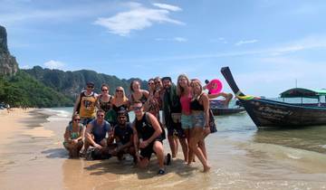 Group of people posing on a beach with clear water.