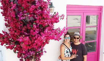 A couple standing in front of a vibrant pink bougainvillea.