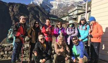 Group of hikers posing with a village and mountains in the backdrop.
