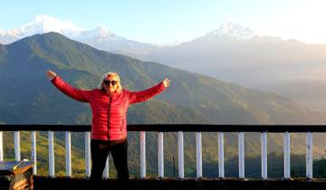 Person with arms outstretched in front of a panoramic mountain view.