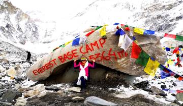 Colorful flags and a marker at Everest Base Camp in snowy surroundings.