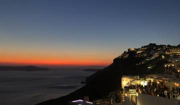 Evening view of Santorini with illuminated buildings and a colorful sky.