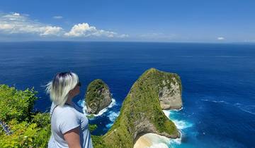 A woman with short hair looking out over a rocky coastline.