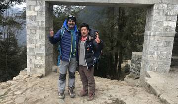 Two people posing under an arched stone structure.