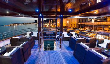 Luxury boat deck at sunset with seating and ocean view.