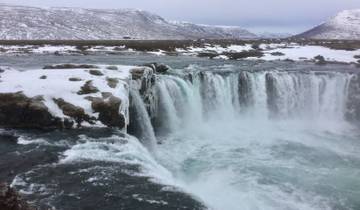 A waterfall cascading in a snowy mountainous landscape.