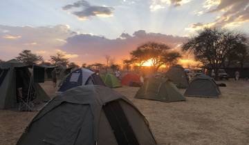 Camping tents set up with a sunset in the background.