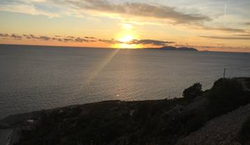 Sunset over the sea with small islands in the distance.