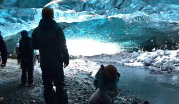 People inside an ice cave with blue ice formations.