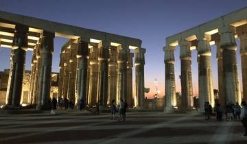 Temple ruins at sunset with illuminated columns.
