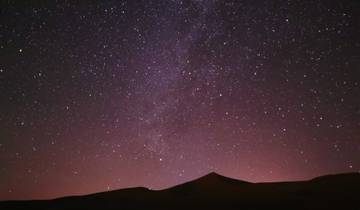Starry night sky over sand dunes.