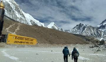 Hikers walking towards Everest Base Camp sign on a rocky path.