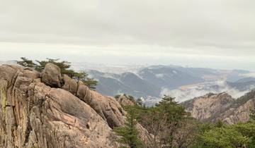 Mountainous landscape with misty hills covered in trees and rocky outcrops.
