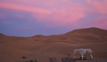 Desert landscape during a colorful sunset with a camp setup.