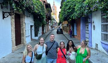 Group of people standing on a street lined with colorful buildings and greenery.