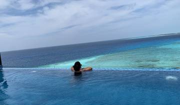 Person relaxing on the edge of an infinity pool overlooking the ocean.