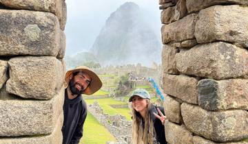 Two people peeking from stone structures with foggy mountains in the background.