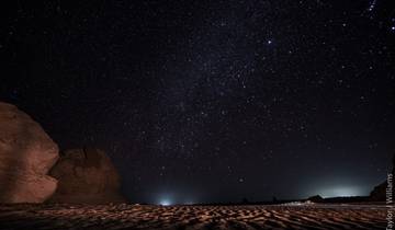 Night sky filled with stars over a desert landscape.