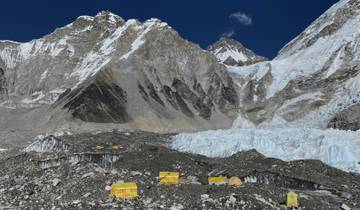 A camp at the foot of a glacier with snow-covered peaks.