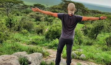 Person with open arms enjoying the view of a green landscape.
