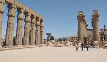 Visitors walking in front of large temple ruins in Luxor.