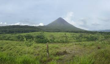A distant volcano surrounded by green fields and hills.