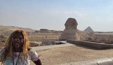 Person standing in front of the Sphinx and a pyramid in the distance.