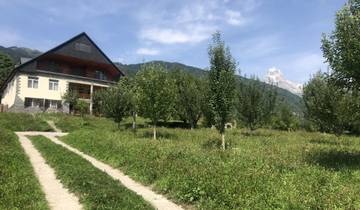 Country house surrounded by green meadows with a mountain view.