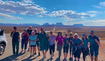 A group of tourists posing in front of a desert landscape.