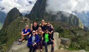 Tour group posing on a rock with Machu Picchu in the background.