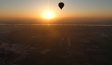 Hot air balloon silhouetted against the sunrise.